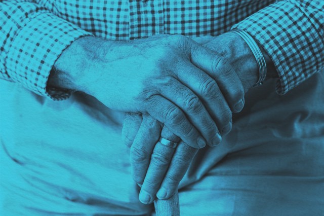 Close-up of an elderly mans hands on a walking stick