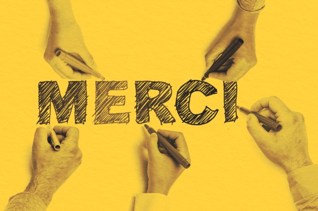 People hold markers while contributing to a colorful sketch of the phrase "Merci"