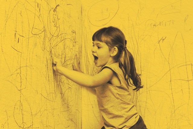 Girl drawing with crayons on the wall