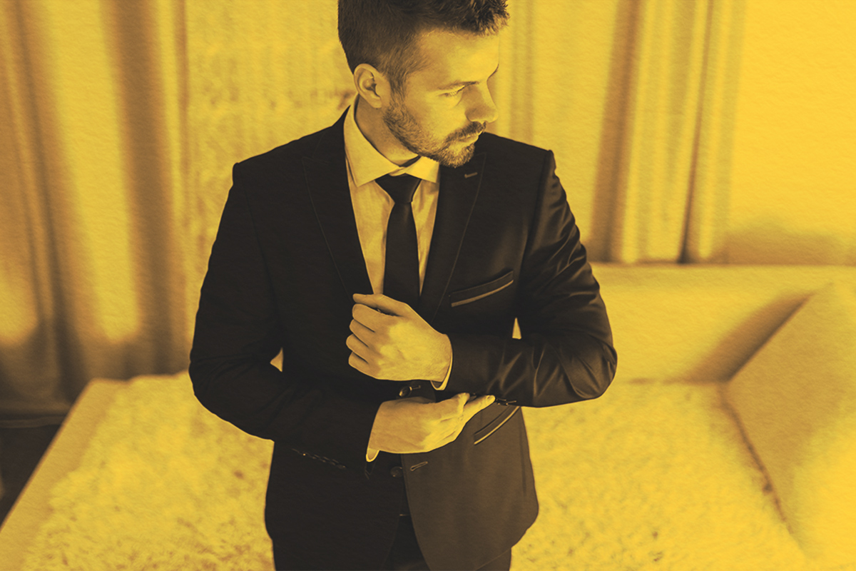 Man tying cufflinks on tuxedo jacket