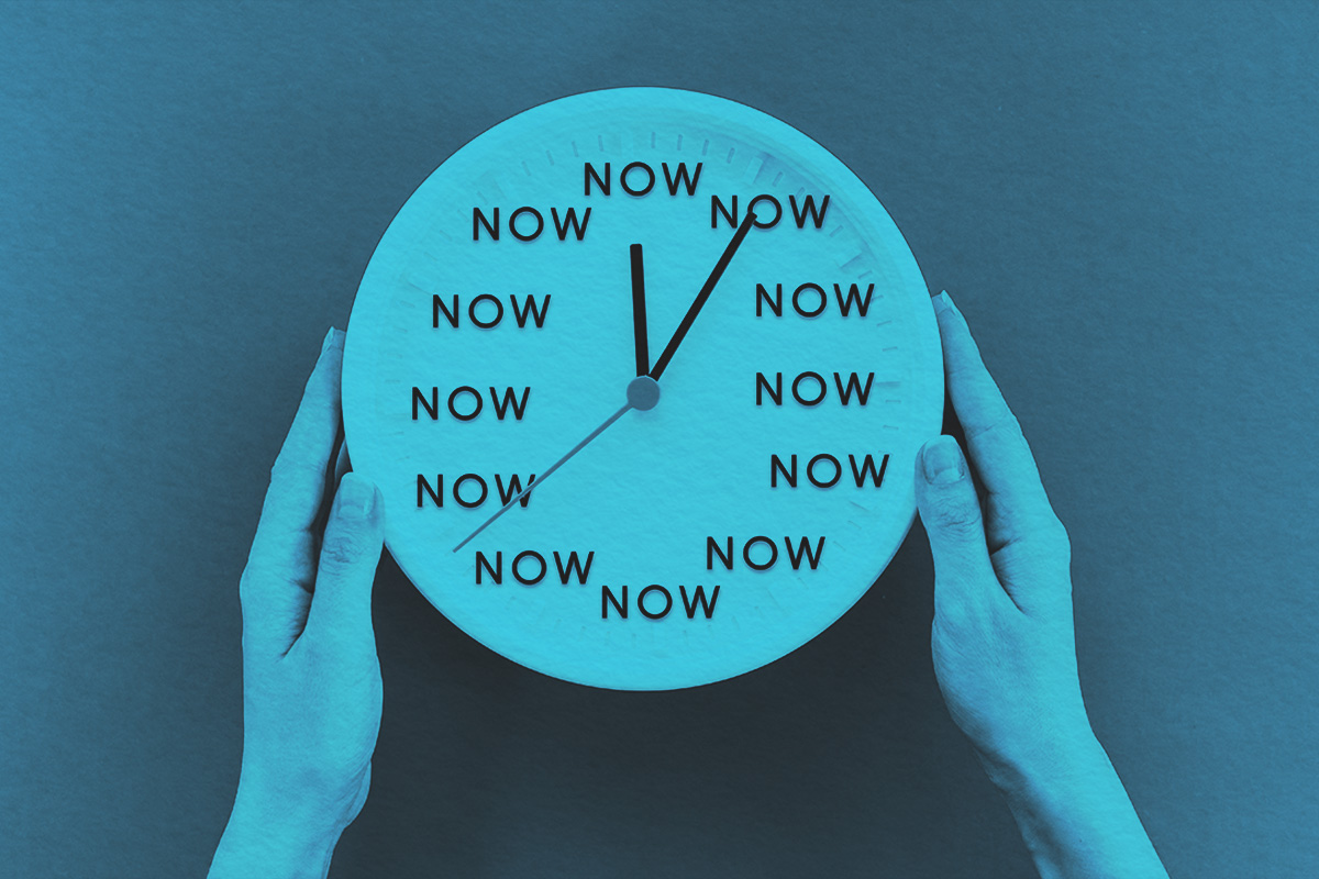 Woman's hands hold a clock with the inscription NOW