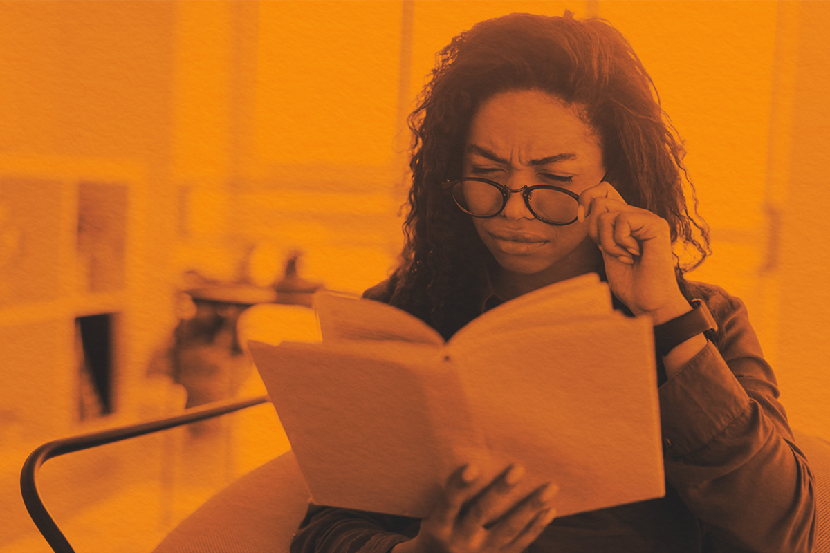 Focused confused young lady trying to read paper book