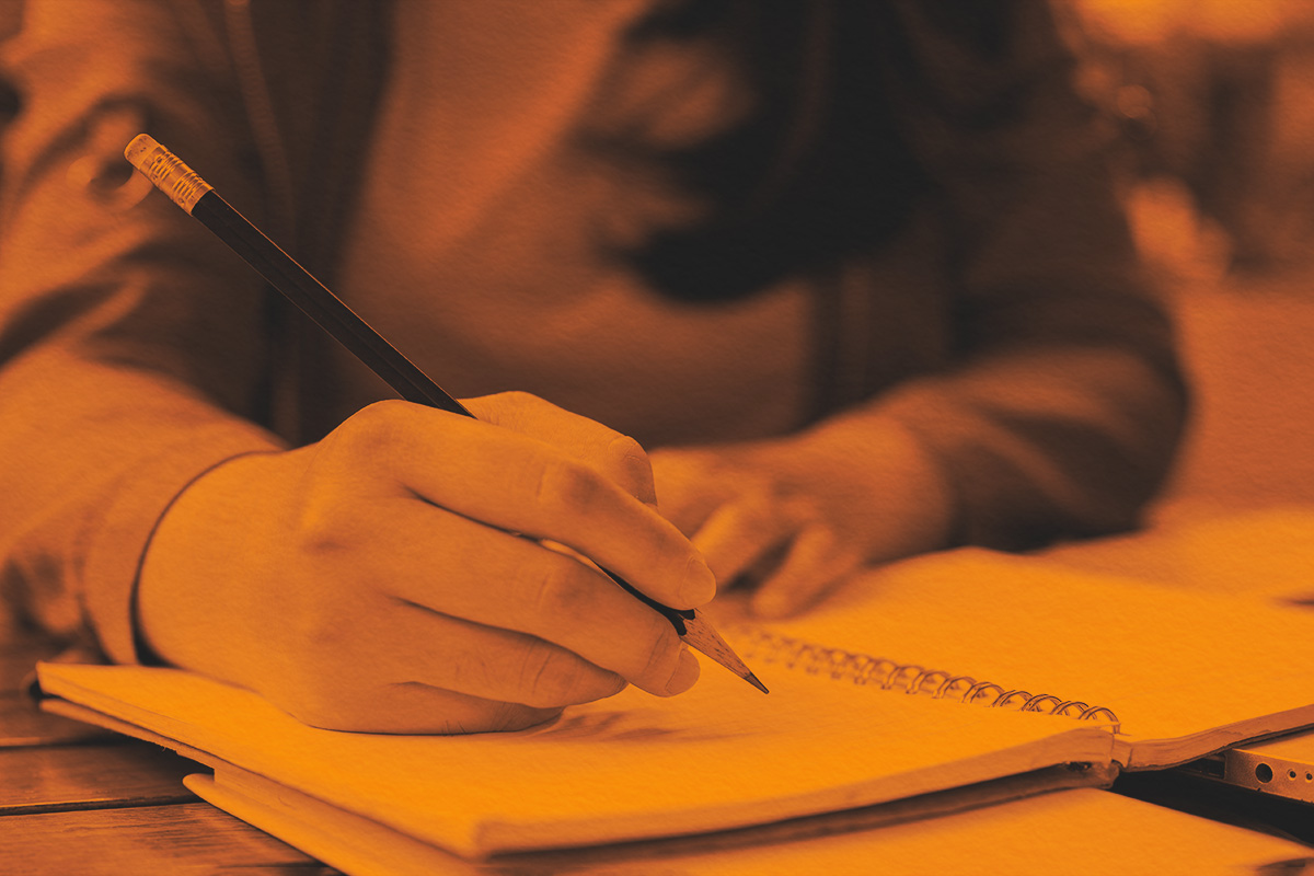 holding a pencil, writing something in a notebook