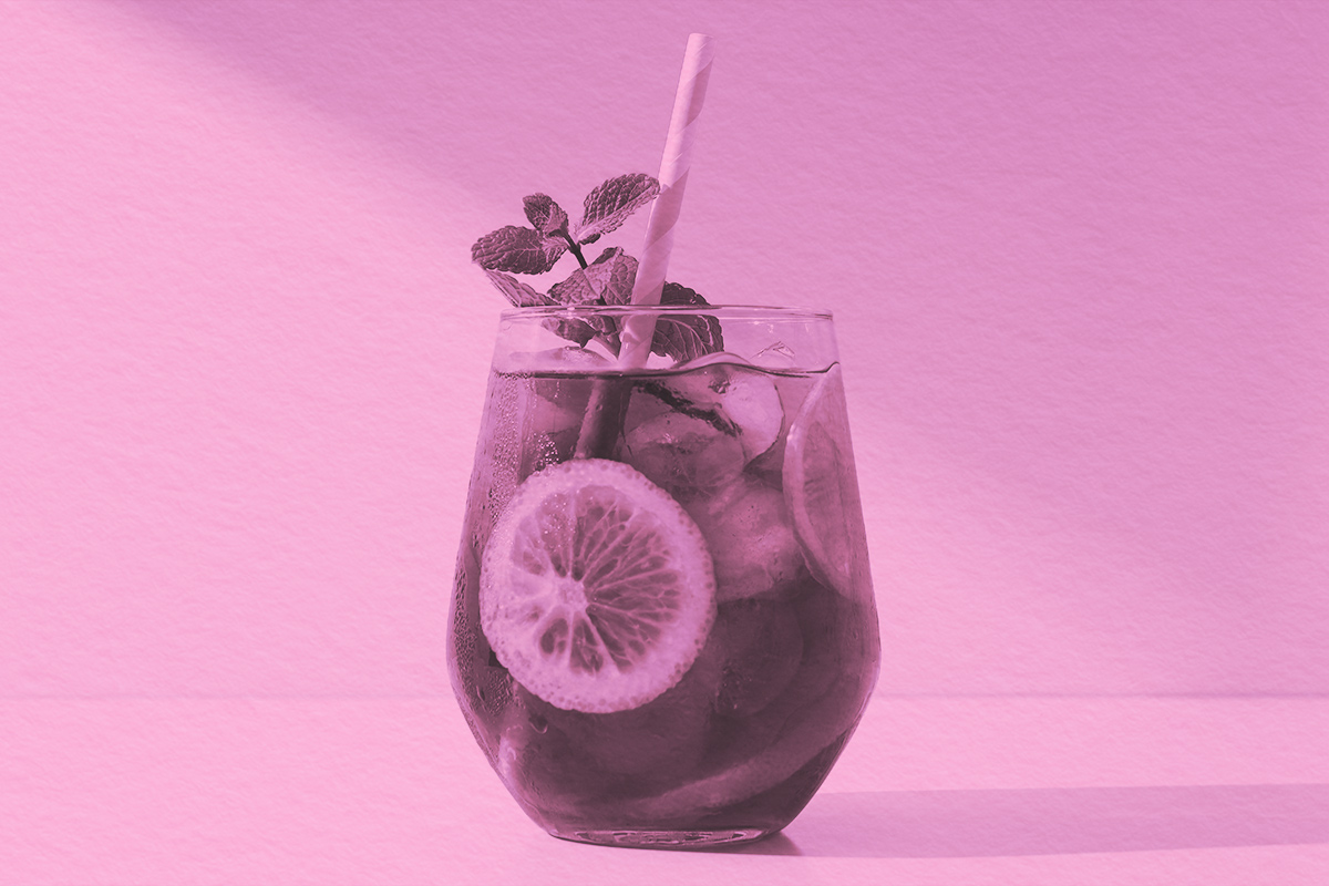 A glass of iced tea with lemon and basil