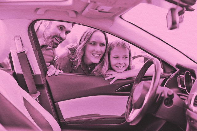 Family of three admiring the interior of a car