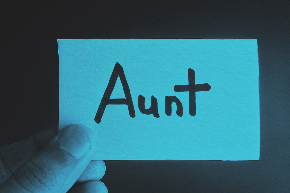 Hand holding a paper card with the word AUNT 